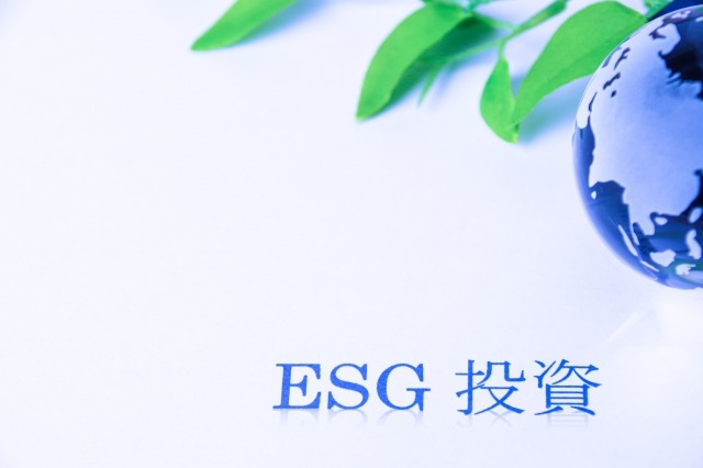 「ESG 投資」文字與玻璃地球儀和綠色植物葉子/環境社會治理投資概念圖/永續金融與企業責任/藍色調的環保主題圖片
